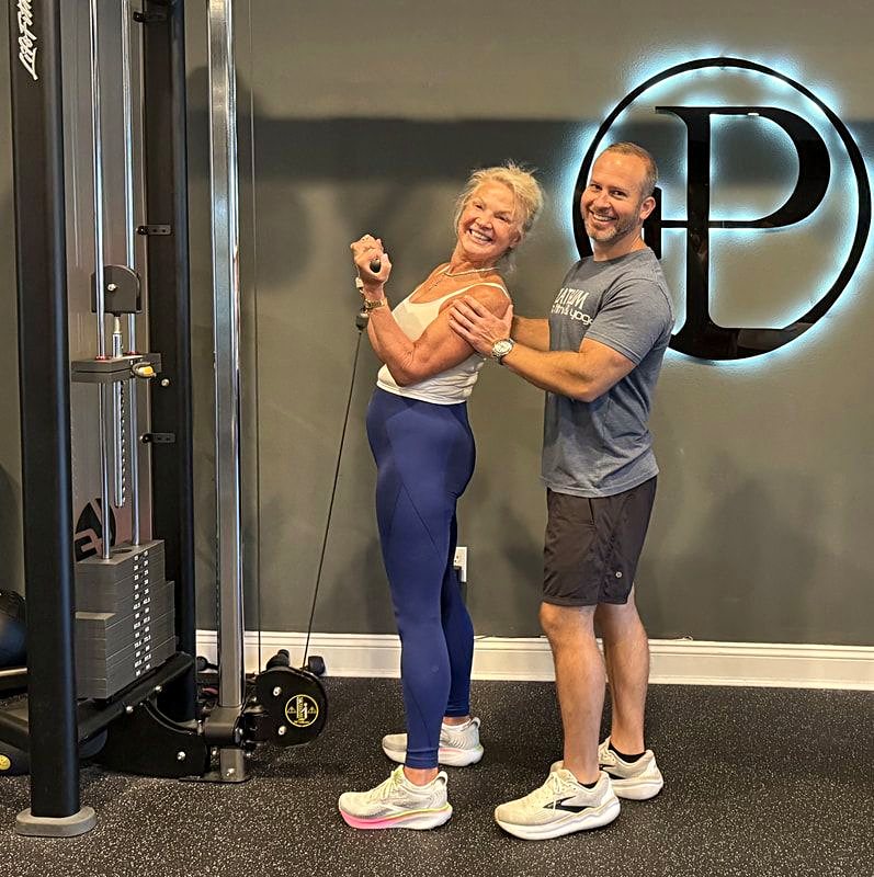 Travis Lightfoot coaching a client on the cable machine at Platinum