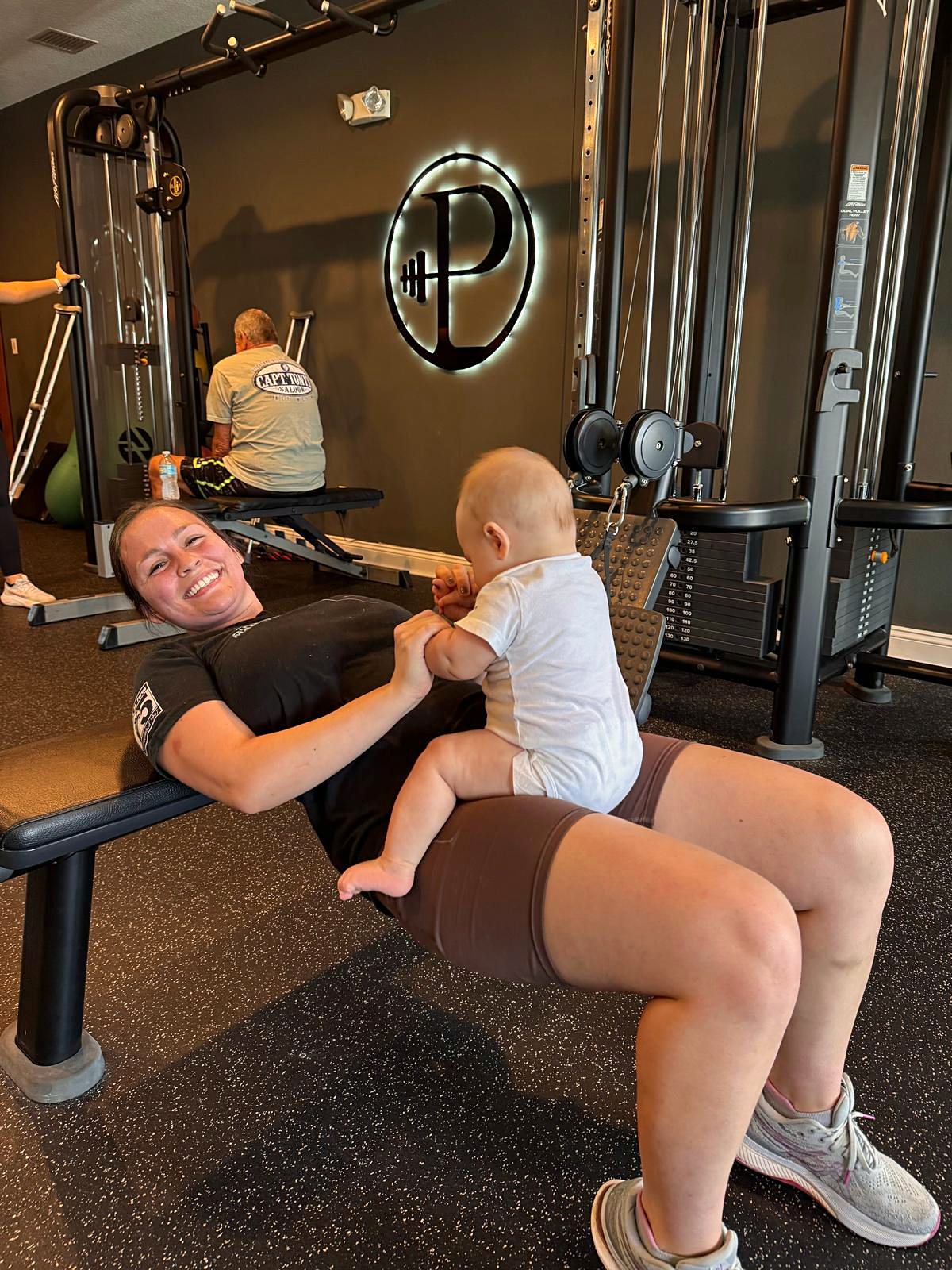 Mom doing a hip thrust with her baby during a postnatal training session